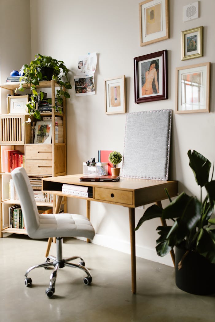 A cozy and tidy home office featuring a wooden desk, lush houseplants, and stylish wall art.